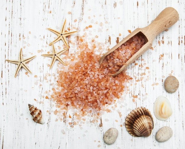 Sal de mar en cuchara de madera con conchas marinas y estrellas de mar