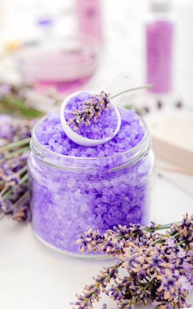 Sal marina de lavanda violeta con flores de lavanda. Productos de baño de lavanda Tratamiento de aromaterapia sobre fondo de madera blanca. Cuidado de la piel spa productos cosméticos de baño de belleza para relajarse.