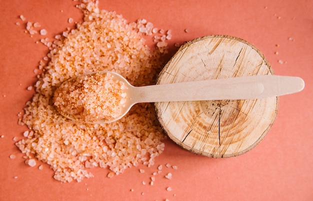 sal marina rosa en una cuchara de madera de cerca.El fondo está hecho de ingredientes y materiales naturales