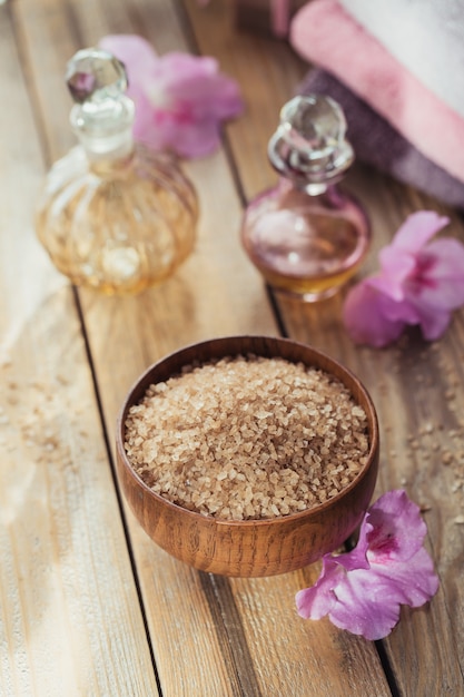 Sal marinho, sabonete artesanal natural, óleo cosmético natural e toalhas coloridas com flores de azaléia na superfície de madeira rústica. Cuidados com a pele, rosto e corpo saudáveis. Conceito de spa e sauna