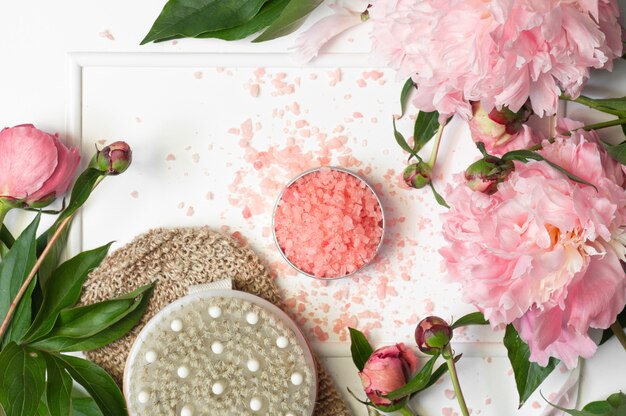 Sal natural para baño con cepillo de masaje seco y flores de peonía.