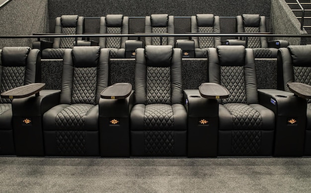 Una sala de cine con un asiento de cuero negro y un asiento negro que dice 'la película está aquí'