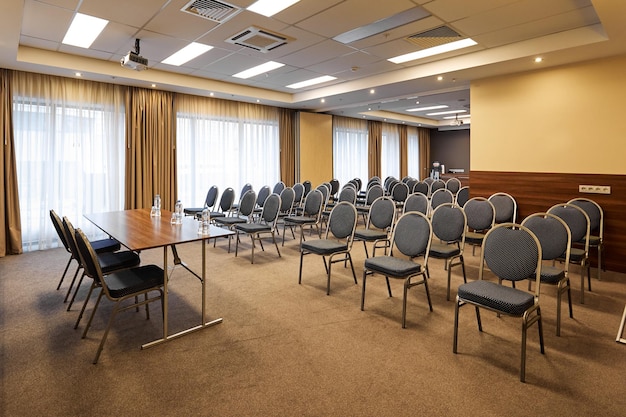 Sala de conferencias vacía con sillas y escritorio para oradores