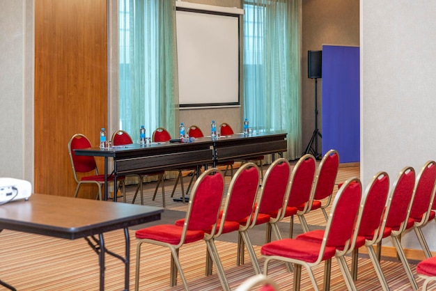 Foto sala de conferencias vacía con tabla y sillas con pancartas de pantalla foro de reuniones de negocios y presentaciones