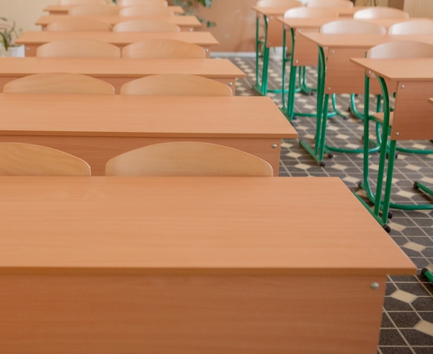 Sala de aula vazia com cadeiras e mesas em uma linha