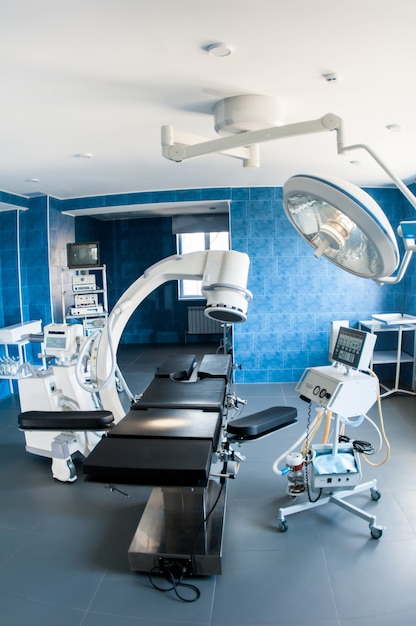 Sala de cirurgia moderna azul com exame médico de raio-x, mesa de operação com lâmpada especial, dispositivos médicos. pesquise o diagnóstico médico e o conceito de tecnologia de cuidados de saúde.