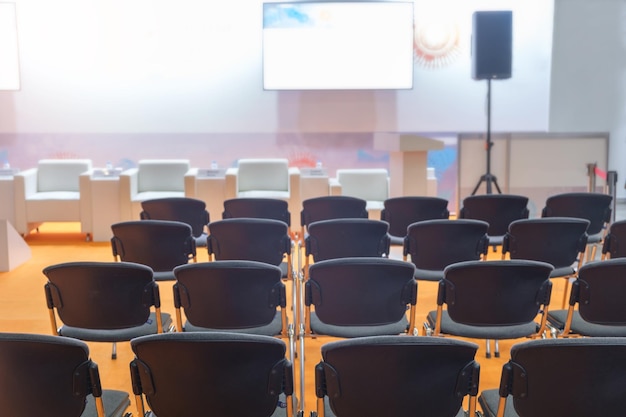 Sala de conferências super com cadeiras pretas e iluminação colorida e tela em branco