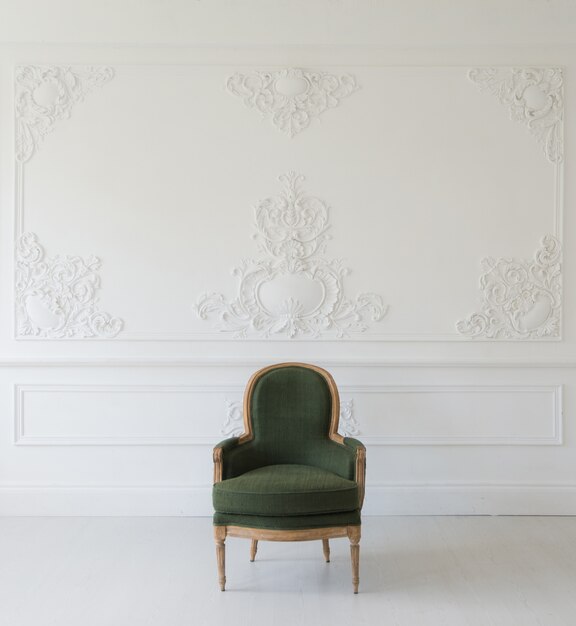 Sala de estar com poltrona verde elegante e antiga em elementos de rocococo de molduras de estuque de baixo-relevo de design de parede branca de luxo