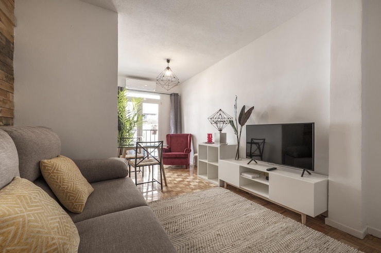 Foto sala de estar decorada com parede de madeira crua em apartamento de aluguel por temporada com aparador branco com tv e piso em parquet de carvalho