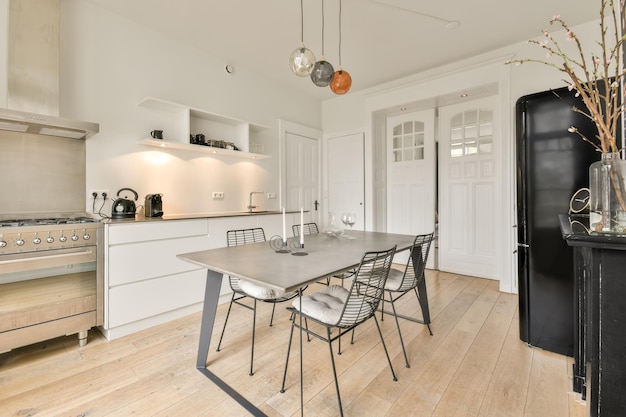 Sala de jantar com móveis de metal ao lado de uma pequena cozinha em branco