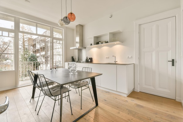 Sala de jantar com móveis de metal ao lado de uma pequena cozinha em branco