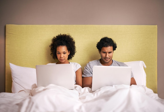 Sala de reuniões do quarto Um jovem casal na cama com seus laptops