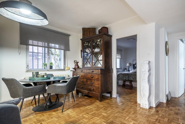 Foto sala de estar en una casa convencional con estantería de madera de raíz de estilo vintage mesa de comedor circular negra y sillas tapicadas a juego