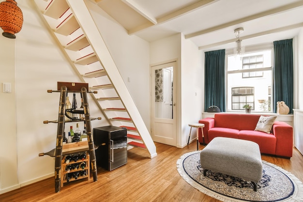 Una sala de estar con una escalera y un sofá rojo.