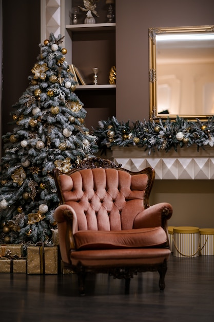 Sala de estar con sillón color beige, árbol de navidad y regalos. Interior de navidad