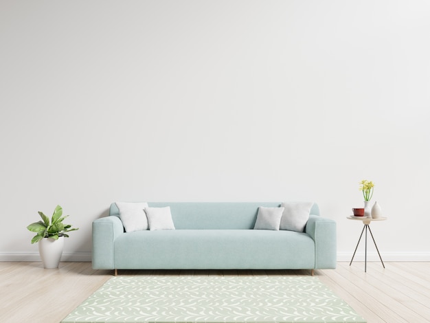 Sala de estar con sofá con almohadas, planta y florero con flores sobre fondo de pared blanca