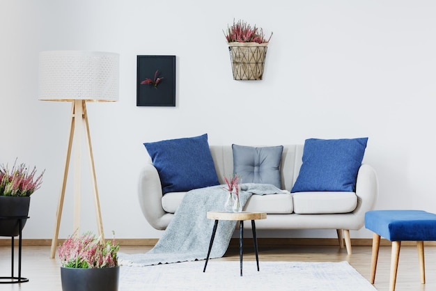 Una sala de estar con un sofá blanco y un soporte de madera con una planta encima.
