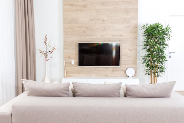 Sala de estar con sofá y tv led en pared de madera