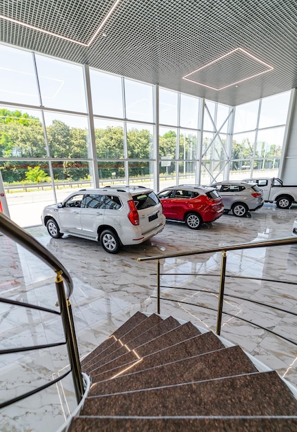 Foto sala de exposiciones del concesionario en un moderno edificio de cristal con coches nuevos. vista desde el segundo piso en los autos a continuación.