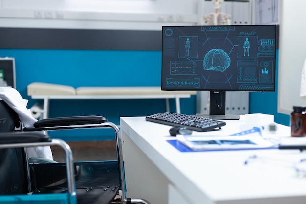 Sala de oficina de hospital brillante y vacía equipada con equipo de examen médico listo para la consulta del paciente. Computadora de pie en la mesa con el esqueleto del cuerpo humano en la pantalla. concepto de medicina