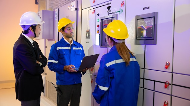 Foto sala de paneles de interruptores eléctricos equipo de ingenieros eléctricos profesionales asiáticos que trabajan con computadoras portátiles para servicio y mantenimiento en la sala de paneles de control hvac en un nuevo edificio moderno