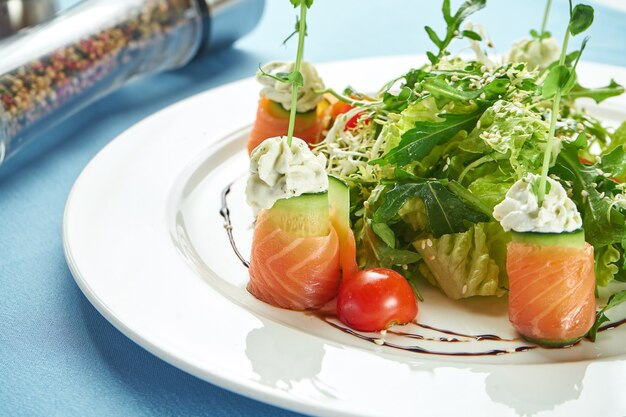 Salada apetitosa com frutos do mar, salmão, rúcula e tomate cereja em um prato branco sobre uma toalha de mesa azul