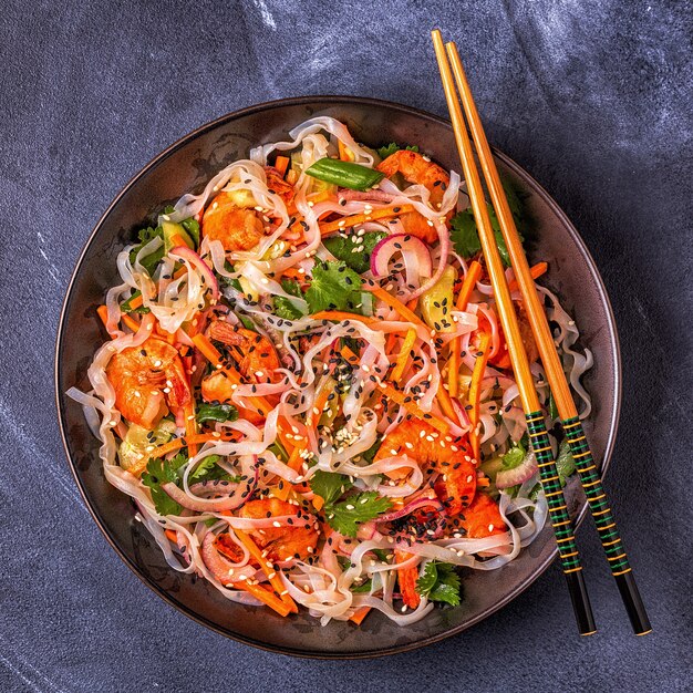 Salada asiática com macarrão de arroz, camarão e legumes, vista de cima.