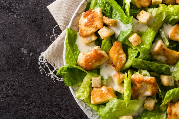 Foto salada caesar com alface, frango e croutons em preto