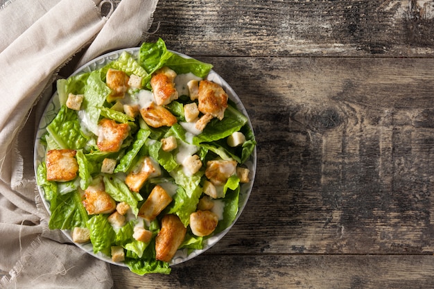 Salada caesar com alface, frango e croutons vista superior de mesa de madeira, copie o espaço