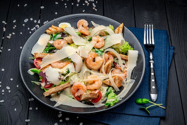 Salada caesar com camarão grelhado em uma vista superior de fundo escuro