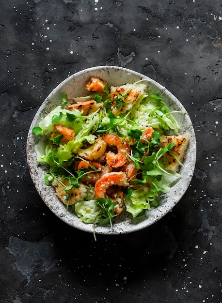 Salada Caesar com camarão grelhado em uma vista superior de fundo escuro