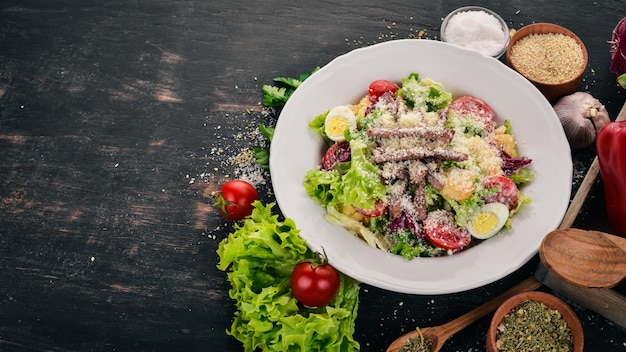 Salada Caesar com carne em um fundo preto de madeira Vista superior Copie o espaço para o seu texto