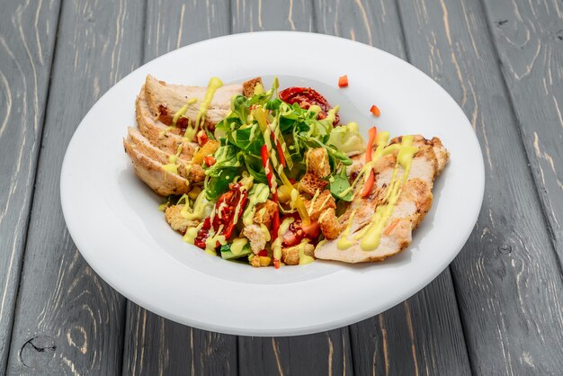 Salada Caesar com croutons, ovos de codorna, tomate cereja e frango grelhado na madeira