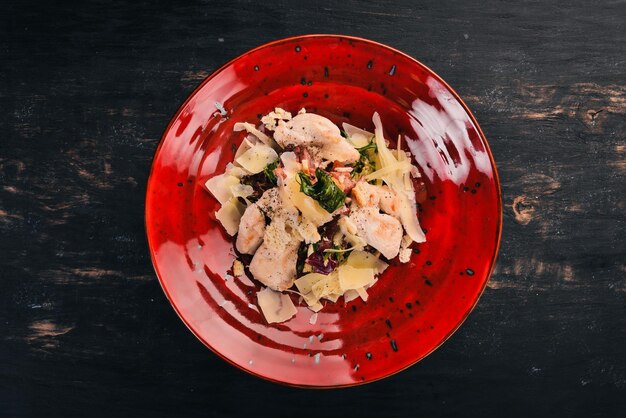 Salada caesar com filé de frango salgadinhos frios em um fundo preto de madeira copie o espaço