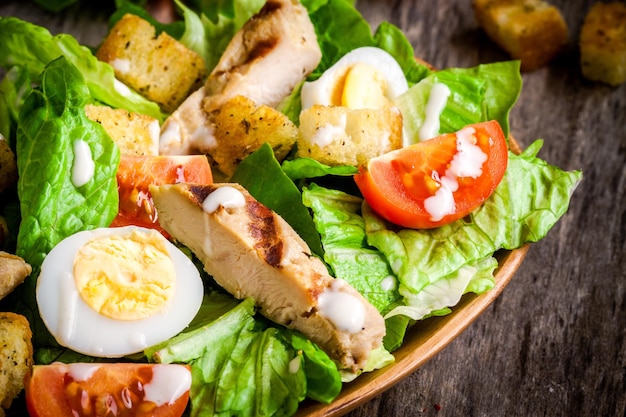 Salada caesar com ovos de codorna tomate cereja e frango grelhado na mesa de madeira