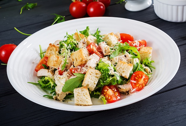 Salada Caesar de frango grelhado saudável com tomate, queijo e pão torrado. Cozinha norte-americana.