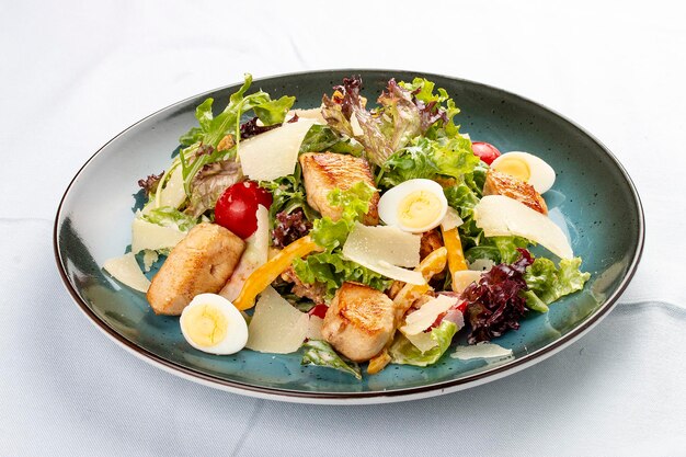 Salada Caesar Deliciosa salada com croutons peito de frango frito queijo parmesão ralado e alface com molho em uma molheira Num prato decorativo