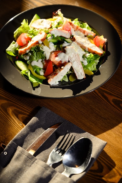 Salada caesar fresca em chapa preta na mesa de madeira escura. Vista do topo.