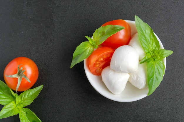 Salada Caprese com tomate maduro e mussarela com folhas frescas de manjericão. Comida italiana.