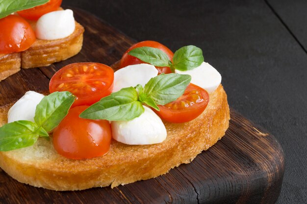 Salada Caprese com tomate maduro e mussarela com folhas frescas de manjericão. Comida italiana.