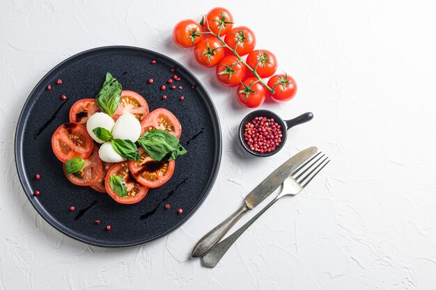 Salada Caprese com tomate, manjericão, salada Caprese com garfo com vinagre balsâmico e azeite de oliva