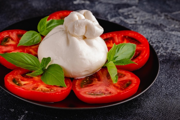 Salada Caprese com tomate, queijo burrata e manjericão Fundo escuro