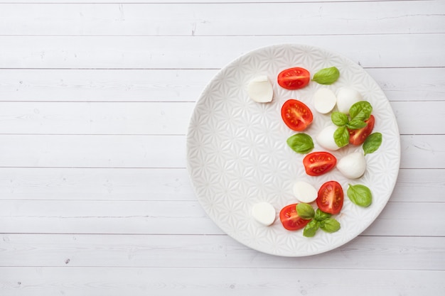 Salada Caprese de tomate, queijo mussarela e manjericão em um prato branco. Cozinha italiana. Espaço da cópia