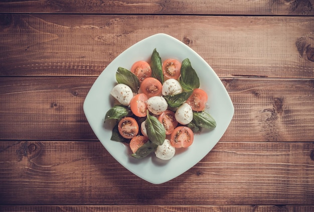 Salada caprese em prato com fundo de madeira