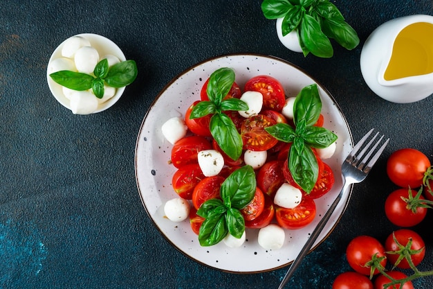 Salada caprese italiana com tomate fatiado mussarela manjericão azeite em um fundo escuro Vista superior Comida italiana Salada saudável Comida de verão