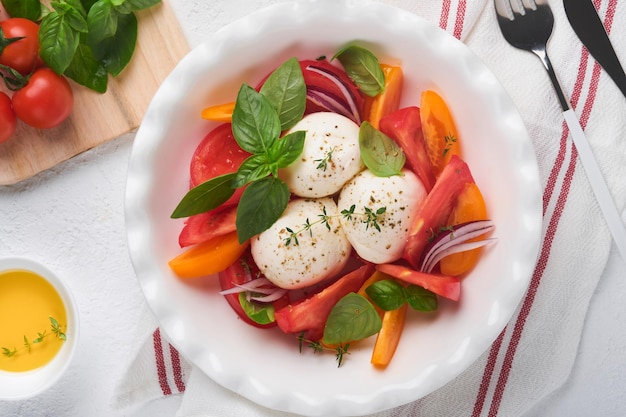 Salada caprese Salada caprese italiana com tomate fatiado queijo mussarela manjericão azeite em chapa branca sobre fundo branco Deliciosa comida italiana Vista superior Estilo rústico