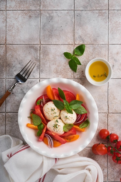 Salada caprese Salada caprese italiana com tomate fatiado queijo mussarela manjericão azeite em chapa branca sobre fundo branco Deliciosa comida italiana Vista superior Estilo rústico