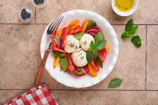 Salada caprese Salada caprese italiana com tomate fatiado queijo mussarela manjericão azeite na chapa branca sobre azulejos de tijolos antigos fundo marrom Deliciosa comida italiana Vista superior Estilo rústico