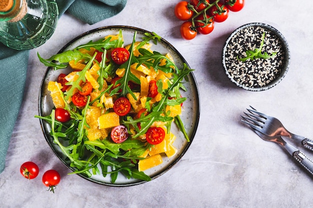 Salada caseira de tomates de cereja laranja e rúcula em um prato na mesa