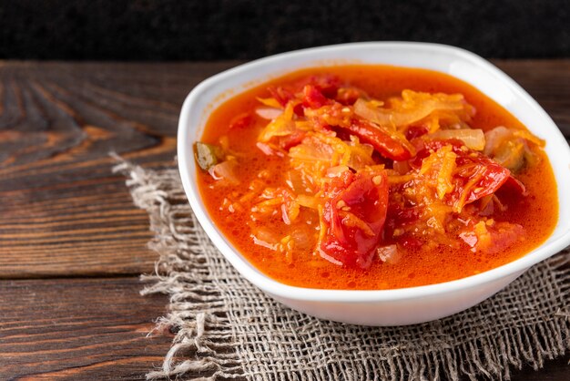 Salada caseira em conserva de tomate, pimenta, cebola e cenoura em madeira escura